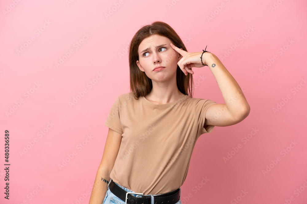Fototapeta premium Young English woman isolated on pink background making the gesture of madness putting finger on the head