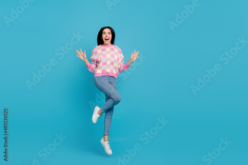 Photo of charming impressed woman wear pink sweater jumping high empty space isolated blue color background