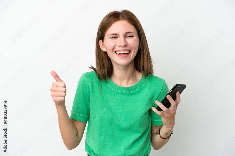 Young English woman isolated on white background using mobile phone while doing thumbs up Young English woman isolated on white background using mobile phone while doing thumbs up