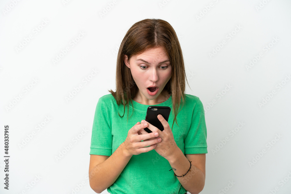Young English woman isolated on white background looking at the camera while using the mobile with surprised expression Young English woman isolated on white background looking at the camera while using the mobile with surprised expression