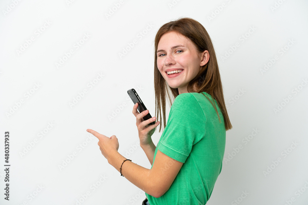 Young English woman isolated on white background using mobile phone and pointing back Young English woman isolated on white background using mobile phone and pointing back