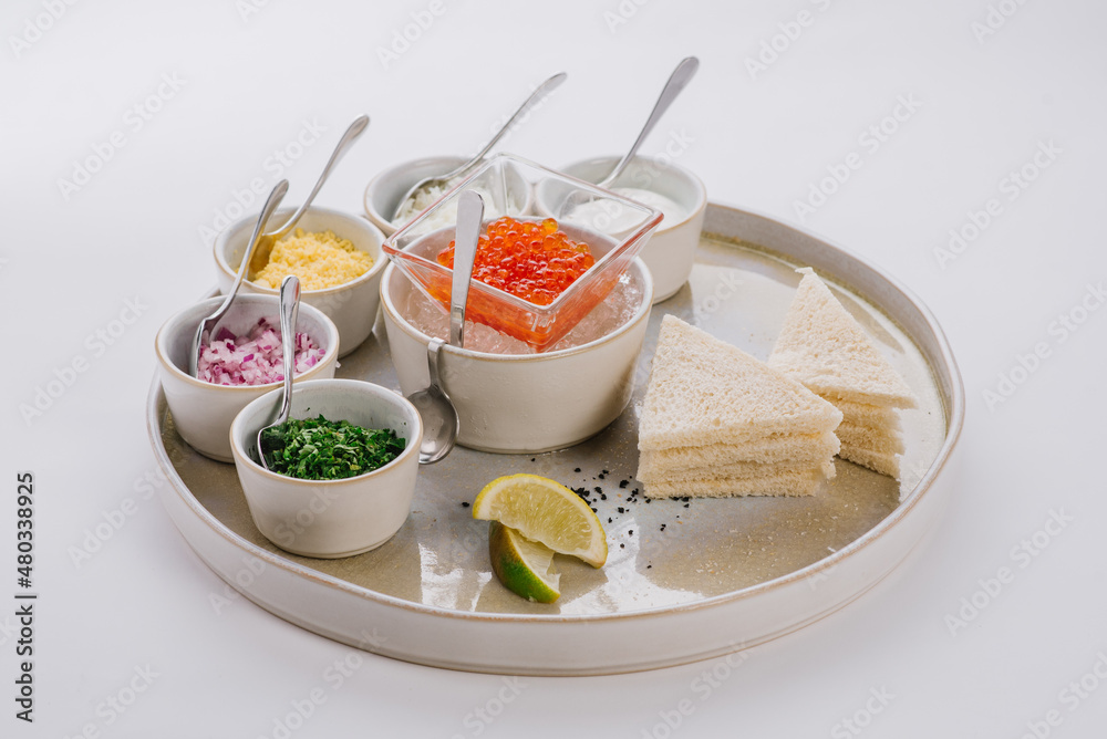 Dish with red caviar and herbs on white background Dish with red caviar and herbs on white background