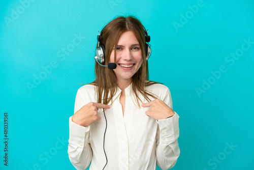 Telemarketer English woman working with a headset isolated on blue background with surprise facial expression