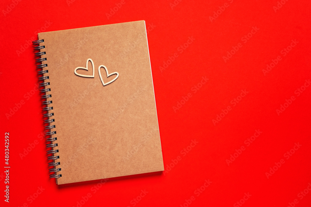 Craft Blank notepad, arrow pensil and wooden hearts on red background. Love message. Valentine's Day and romantic holiday concept. Top view, flat lay with copy space. Craft Blank notepad, arrow pensil and wooden hearts on red background. Love message. Valentine's Day and romantic holiday concept. Top view, flat lay with copy space.