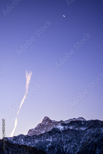 Vertical cloud trail at sunrise over snow coverd mountains