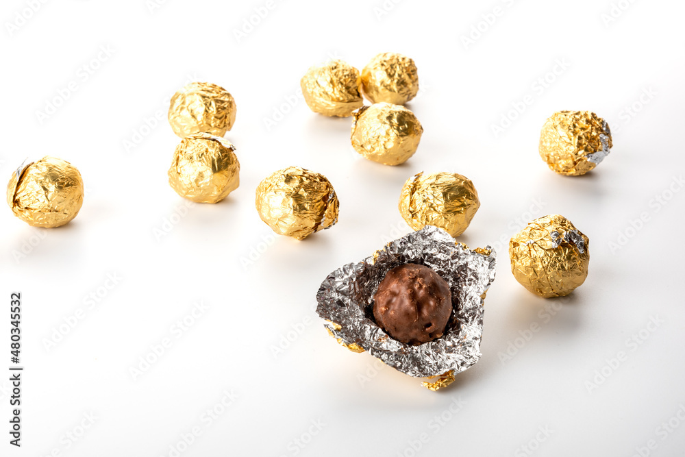 chocolate pralines in wrapper gold foil isolated on white