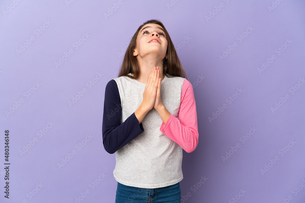 Little girl isolated on purple background keeps palm together. Person asks for something Little girl isolated on purple background keeps palm together. Person asks for something