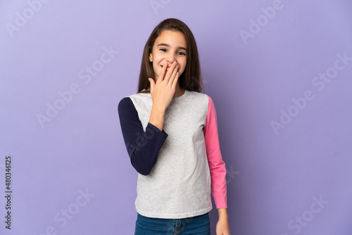 Little girl isolated on purple background happy and smiling covering mouth with hand