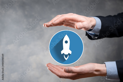 Startup business concept, Businessman holding in hand icon rocket is launching and soar flying out from screen with network connection on dark.flat icons with long shadows.Profit, rise, development.