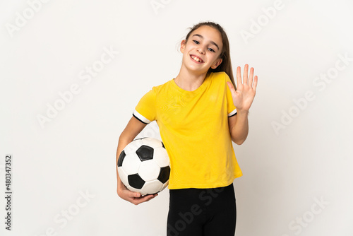 Little football player girl isolated on white background saluting with hand with happy expression © luismolinero