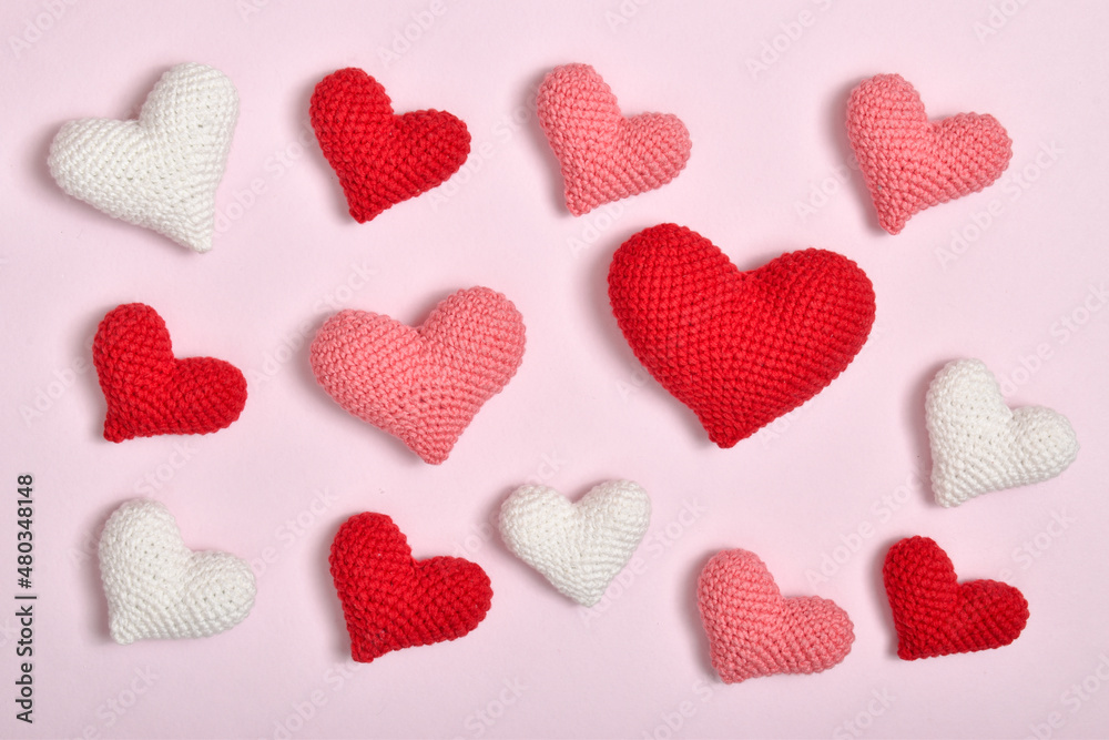A bunch of hearts of different colors in a row lies on a pink background. Background for Valentine's Day. A postcard, a banner for February 14 with a place to copy.