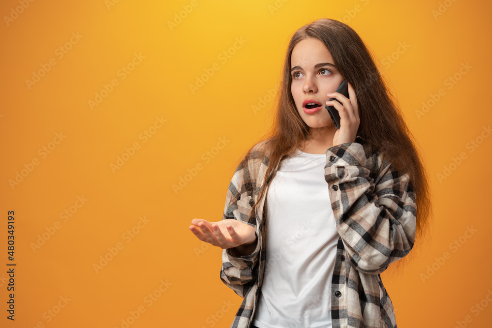 Pretty teenage girl talking on the mobile phone against yellow background Pretty teenage girl talking on the mobile phone against yellow background