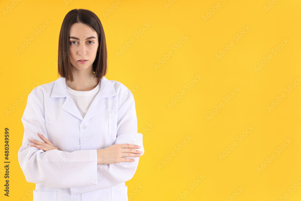 Attractive female trainee doctor on yellow background Attractive female trainee doctor on yellow background