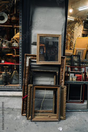 Mirrors and picture frames stand next to an antique shop