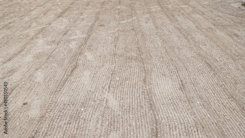 The texture of sand on the beach. Sand leveled with a rake. The concept of cleaning the territory.