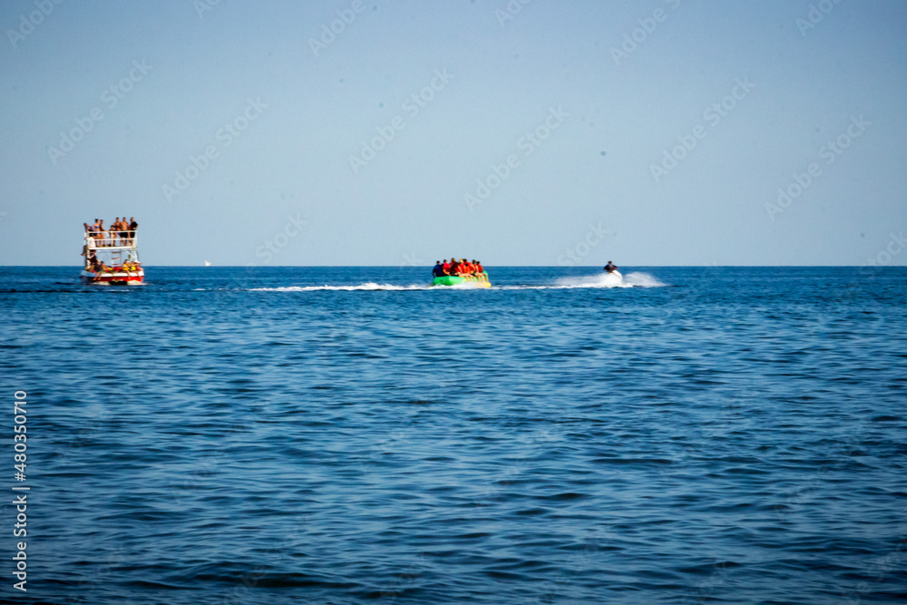 people on a pleasure boat, a jet ski, an inflatable banana in the sea
