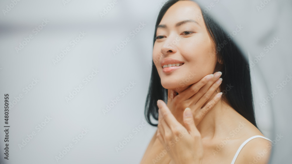Portrait of Beautiful Asian Woman Gently Applying Face Cream Looking in Bathroom Mirror. Young Adult Female Makes Her Skin Soft, Smooth, Wrinkle Free with Natural Cosmetics Skincare Product Portrait of Beautiful Asian Woman Gently Applying Face Cream Looking in Bathroom Mirror. Young Adult Female Makes Her Skin Soft, Smooth, Wrinkle Free with Natural Cosmetics Skincare Product