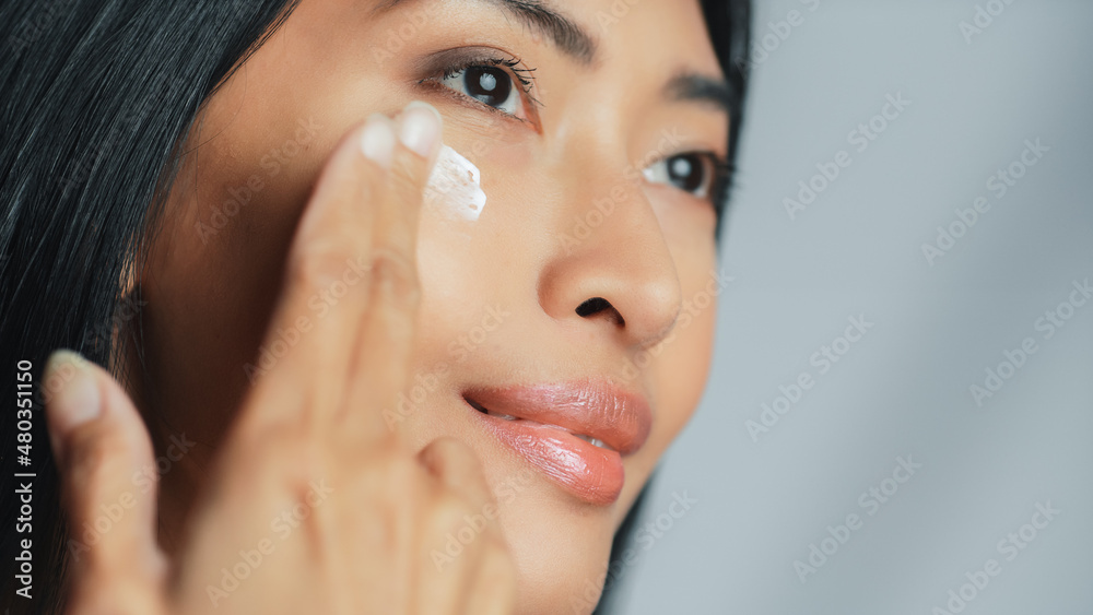 Beautiful Asian Woman Gently Touching Her Face, Looking Away. Young Adult Female with Lush Black Hair Makes Her Skin Soft, Clean with Natural Cosmetics Skincare Product. Close-up Portrait Beautiful Asian Woman Gently Touching Her Face, Looking Away. Young Adult Female with Lush Black Hair Makes Her Skin Soft, Clean with Natural Cosmetics Skincare Product. Close-up Portrait