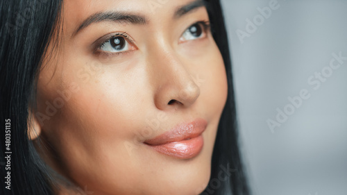 Close-up Portrait Shot of a Beautiful Asian Woman Looking Up. Young Adult Female with Lush Black Hair With Clean Soft Skin. Close-up Portrait