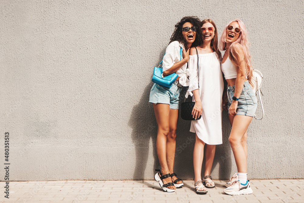 Three young beautiful smiling female in trendy summer clothes.Sexy carefree multiracial women posing on the street background near wall.Positive models having fun in sunglasses. Cheerful and happy Three young beautiful smiling female in trendy summer clothes.Sexy carefree multiracial women posing on the street background near wall.Positive models having fun in sunglasses. Cheerful and happy