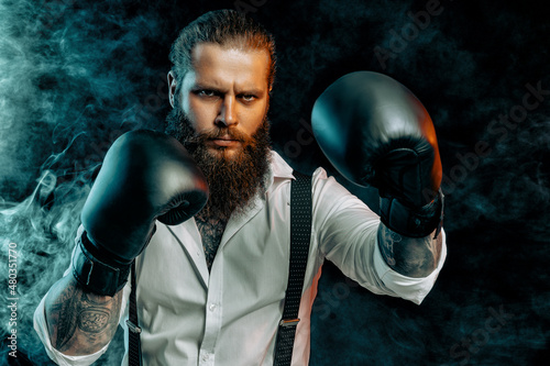bearded man in white shirt wears boxing gloves and ready to fight. Man self defense. Studio shot