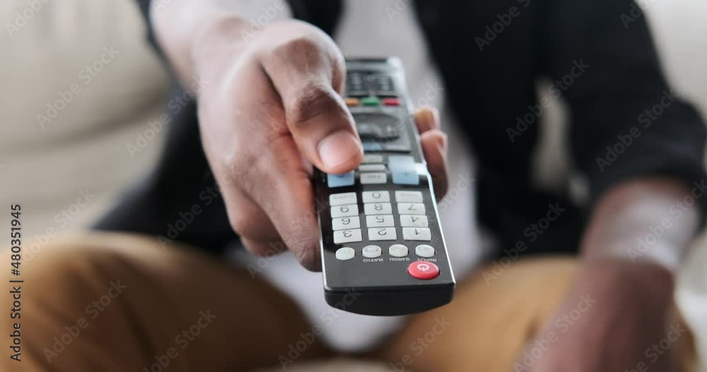 Male hand using remote control to change channels on television at home