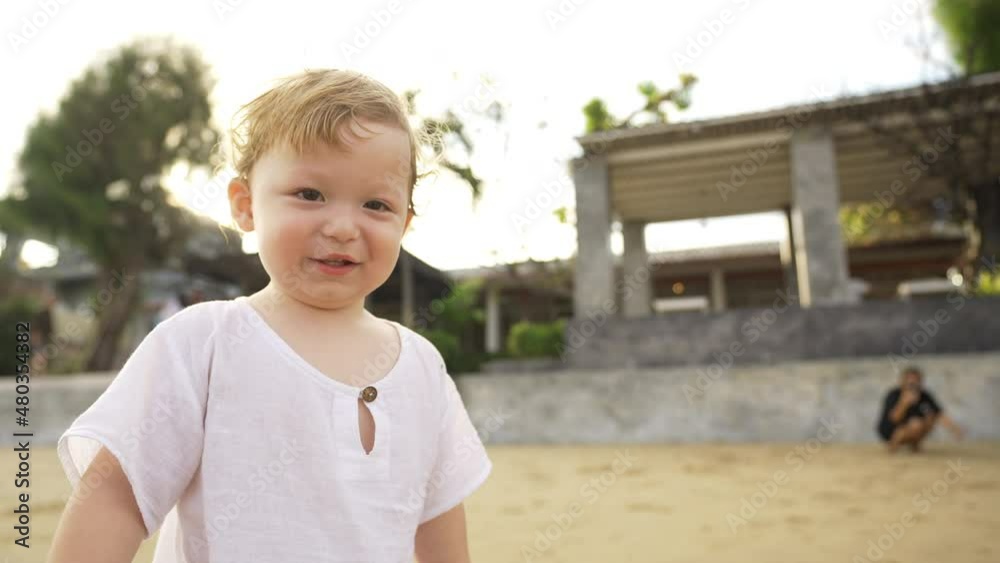 4K Portrait of Cute Caucasian baby boy toddler walking and playing on the beach in summer sunny day. Happy family with little child boy kid enjoy outdoor lifestyle activity on holiday travel vacation