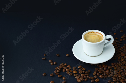 Cup of hot black coffee and roasted coffee beans on table on a black background. Espresso, coffee card