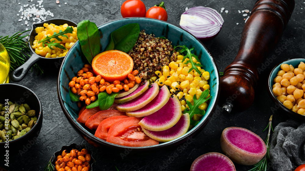 Buddha bowl: quinoa, spinach, corn, tomatoes and watermelon radish, sea buckthorn. Healthy vegetarian eating, super food. Top view On a stone background. Buddha bowl: quinoa, spinach, corn, tomatoes and watermelon radish, sea buckthorn. Healthy vegetarian eating, super food. Top view On a stone background.