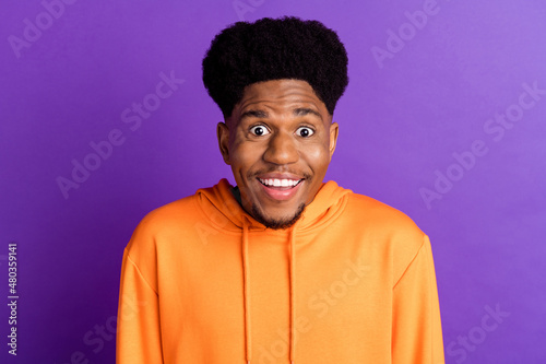 Photo of funky brunet young guy look wear orange hoodie isolated on violet color background