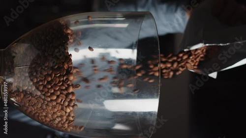 Close up of barista pours coffee beans into a coffee grinder from package in slow motion. Vertical video template for smartphone web promo. photo