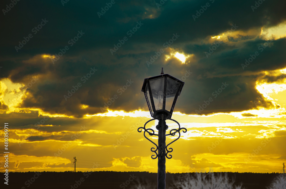 Street lamp on the embankment at sunset. Lantern on sunset sea coast. Sunset streetlamp beach scene. Street lamp on sunset beach