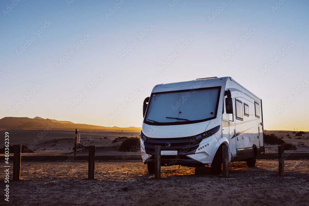 Big motorhome camper parked off road with desert and blue sky in background. Travel lifestyle camping car and freedom. Van against sunlight parked off road. Concept of wanderlust vanlife travelers