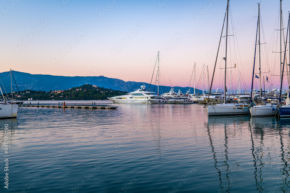 Pier with motorboats and yachts moored alongside at sunset