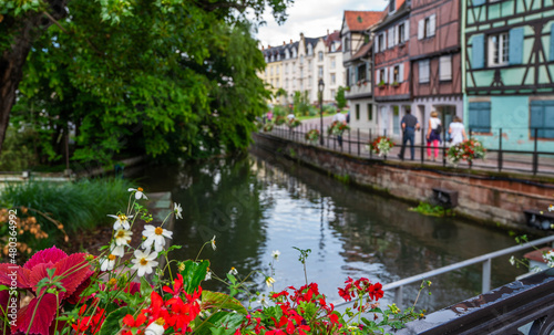 Beautiful flowers at water canal and traditional half timbered houses. Charming old town on a sunny bright day. Beautiful view of colorful romantic city France.