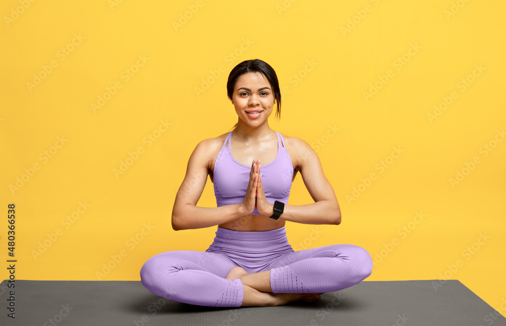 Morning yoga concept. Happy african american lady practicing meditation in lotus position, sitting on mat