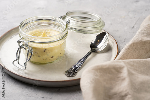 Mason jar with tasty herb butter with grated truffles on scandi plate on grey concrete surface photo