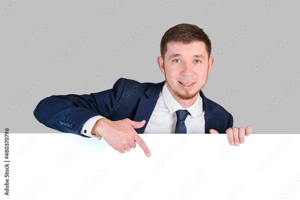 The businessman points with his index finger at the white blank board The businessman points with his index finger at the white blank board