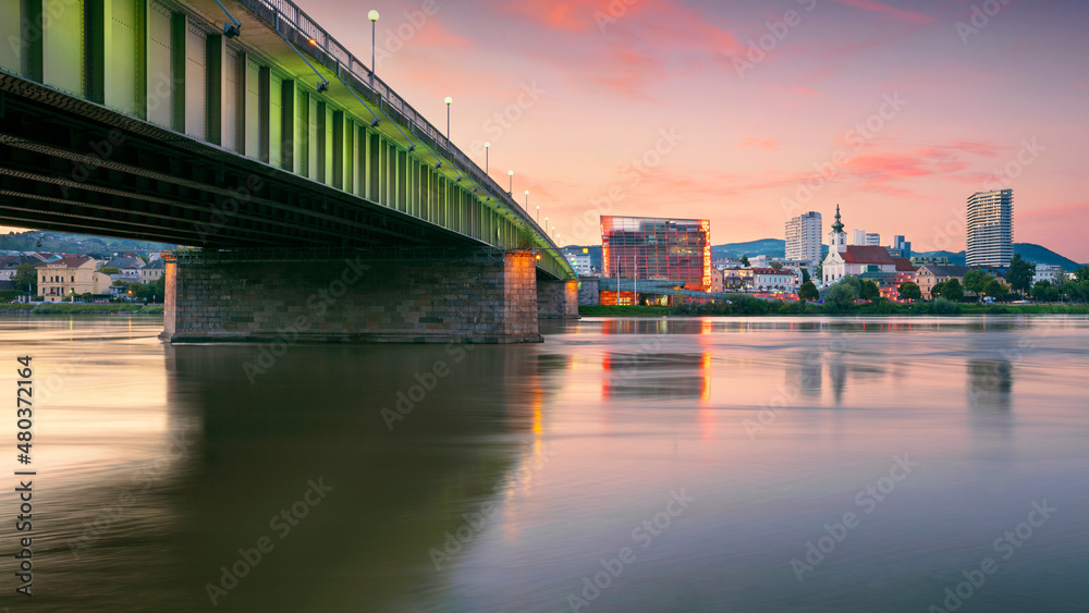 Linz, Austria. Cityscape image of riverside Linz, Austria at summer sunset with reflection of the city lights in Danube river.