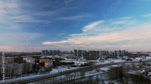 Flying over a snowy park. The city is visible on the horizon. Aerial photography.