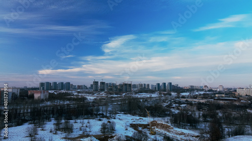Flying over a snowy park. The city is visible on the horizon. Aerial photography.