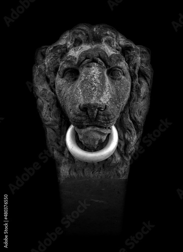 isolated lion head made of stone with a metal ring as part of a decorative facade of a house entrance