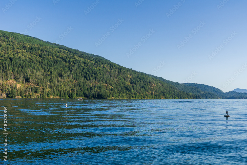 Cultus lake blue water with clear sky and mountains in the distance summer time