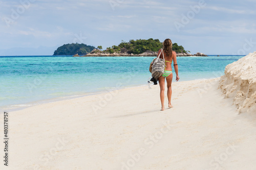 Woman In bikini with beach bag walking on the beach in tropical island.