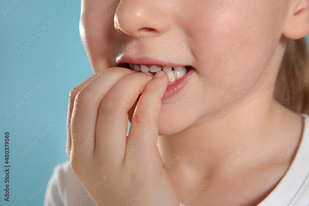 Obraz premium Little girl biting her nails on turquoise background, closeup