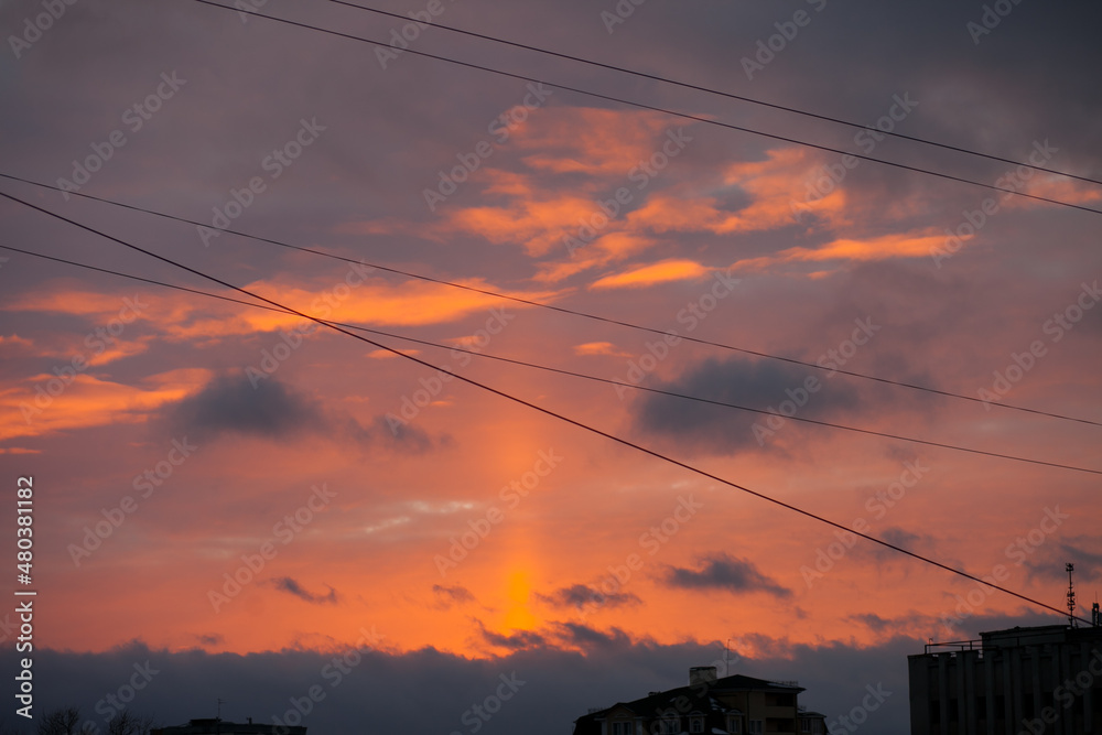Bright colorful sunset through the wires over the city with dark silhouettes of the buildings. Horizontal sky backgroud at sunset or sunrise
