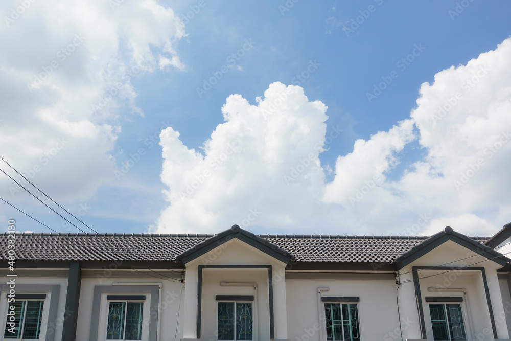 Gray tile roof on house in front of a clear blue sky on a sunny day background.