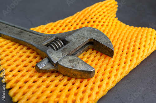 Old adjustable wrench for tightening nuts close-up on a yellow mat