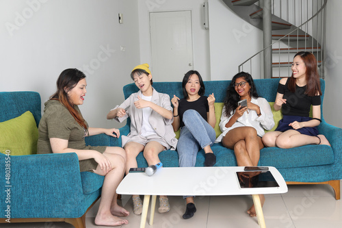 Young Asian woman group talk gossip chat sing party fun enjoy on blue living room sofa