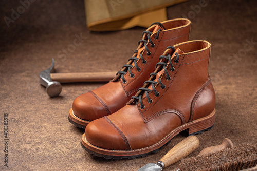 Handcrafted brown leather shoes with cobbler tools on the backgound